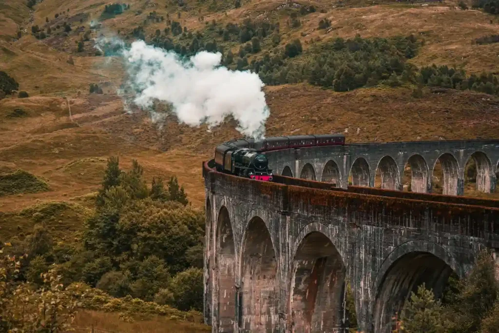 Jacobite Steam Train crossing Glenfinnan Viaduct in Scotland, a famous Harry Potter filming location