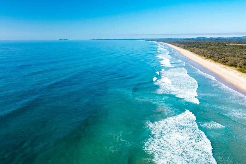 Aerial view of long sandy coastline and blue waves – one of the hidden beaches in Australia