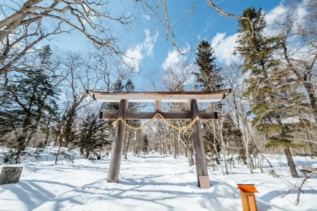 4.compressed_torii_gate_final_under100 Snow-covered torii gate in a peaceful winter forest in Japan, representing the serene beauty of visiting during the cheapest time to go to Japan.