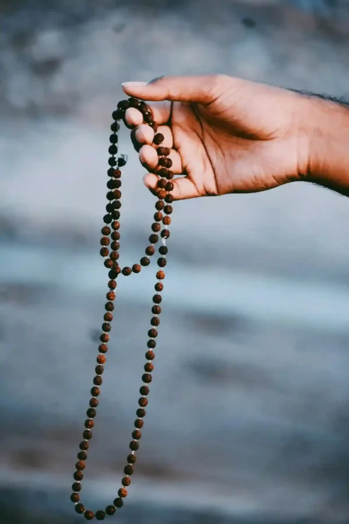 “Hand holding a rudraksha mala – prayer beads used for meditation and chanting in Hindu spiritual practices”