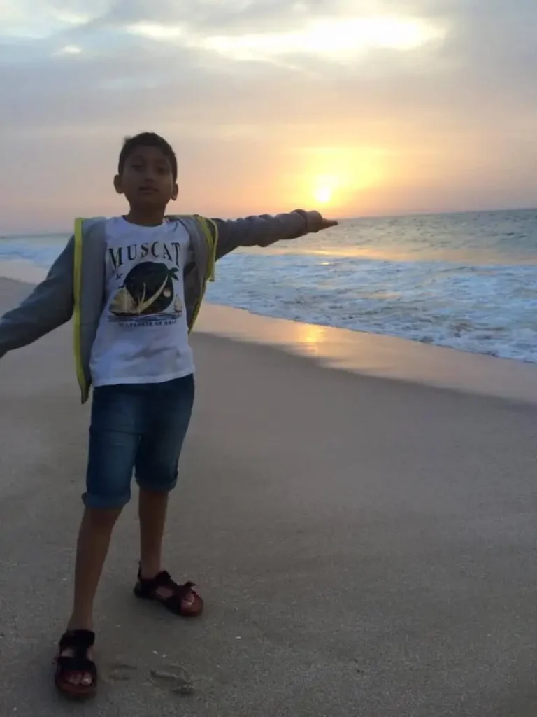Young boy posing playfully at sunset on a serene beach in Oman, showcasing one of the best things to do in Oman — enjoying peaceful coastal moments.