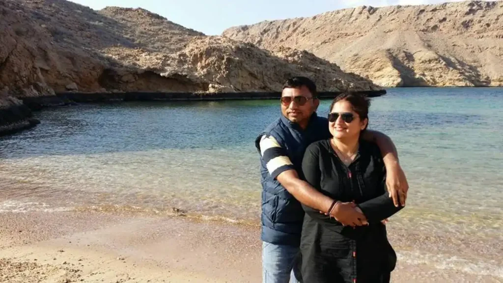 Couple enjoying a peaceful moment on a secluded beach cove surrounded by rocky cliffs and turquoise waters near Muscat, Oman – a serene highlight of Oman travel.






